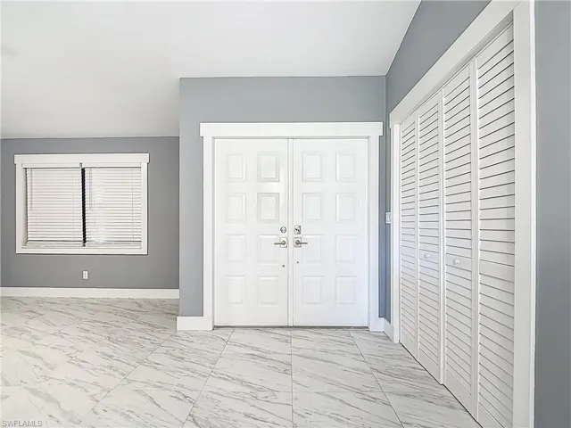 Entryway with light marble finish floors and baseboards