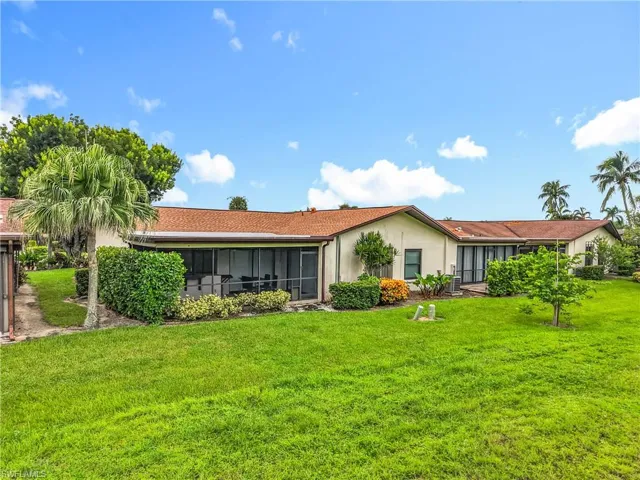 Rear view of property with a lawn, stucco siding, and a sunroom
