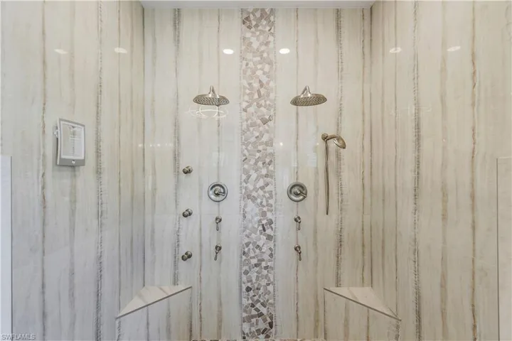 Beautifully updated custom walk in shower with dual rain shower heads, seating and pebbled accent floor.
