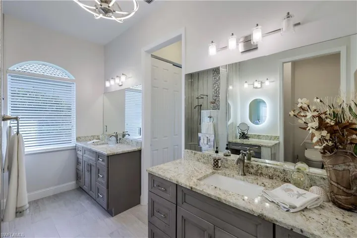 Custom bath updated with new flooring, walk in shower, washed gray cabinetry with granite counter tops, dual sinks, updated lighting, custom vanity area & additional storage.