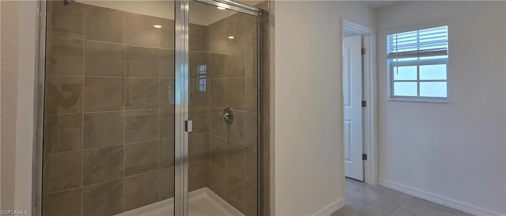 Full bath featuring a shower stall and light tile patterned floors