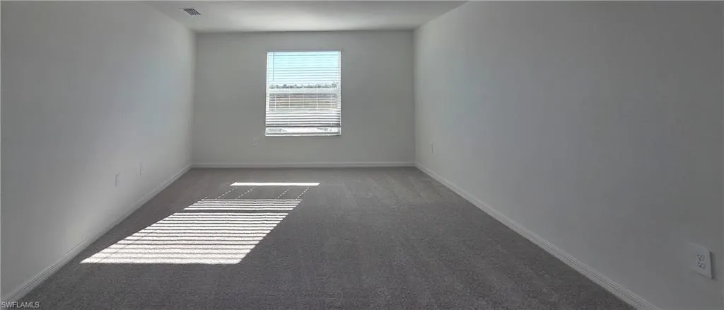 Unfurnished room with baseboards and dark colored carpet
