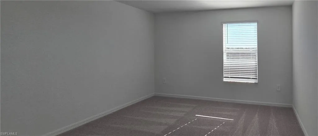 Spare room with dark colored carpet and baseboards