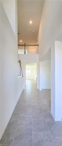 Hall featuring a high ceiling, stairway, recessed lighting, and light tile patterned floors