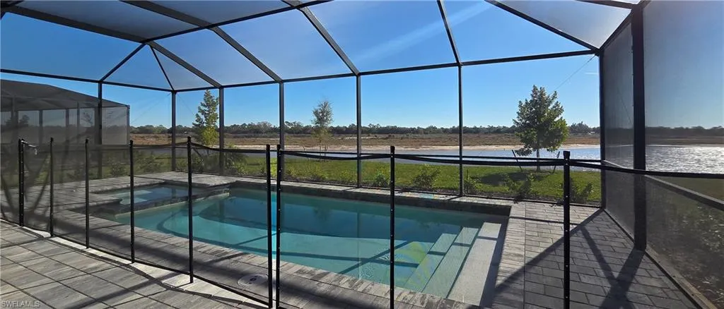 View of pool with glass enclosure, a sunroom, a water view, and a pool with connected hot tub