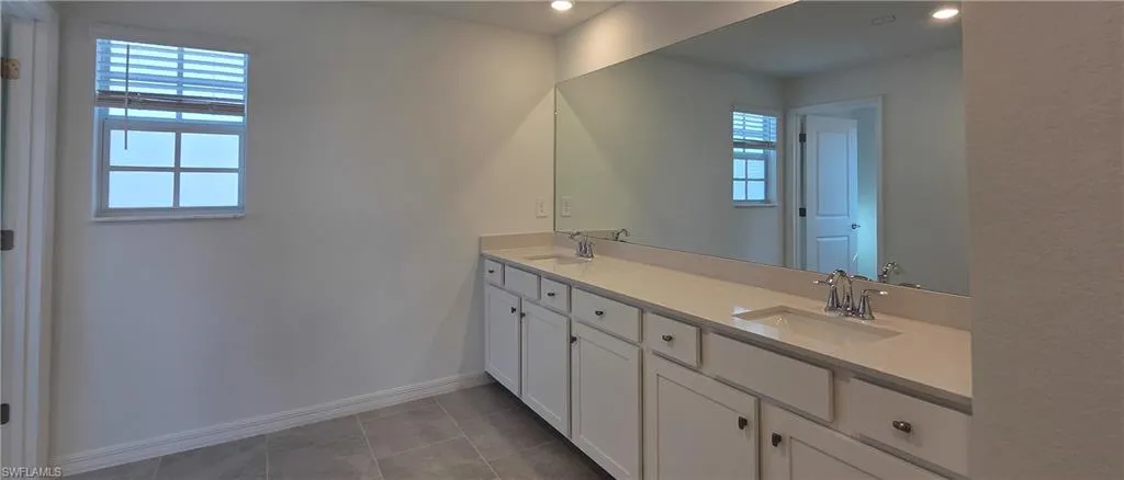 Full bath with double vanity, light tile patterned flooring, and recessed lighting