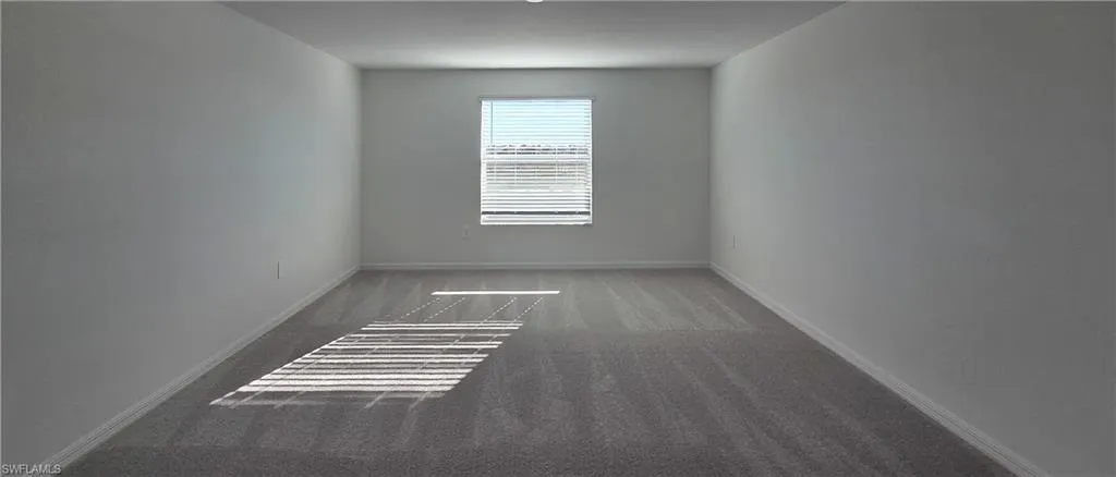 Spare room with dark carpet and baseboards