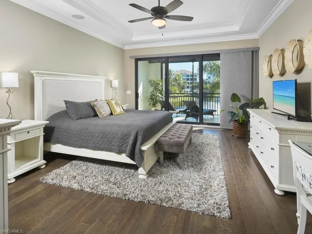 Bedroom with crown molding, dark hardwood / wood-style floors, access to outside, and a raised ceiling