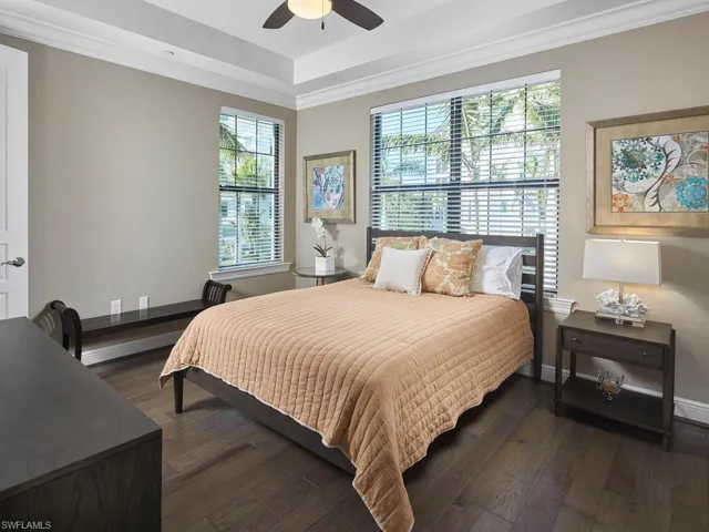 Bedroom with multiple windows, dark wood-type flooring, ornamental molding, and ceiling fan