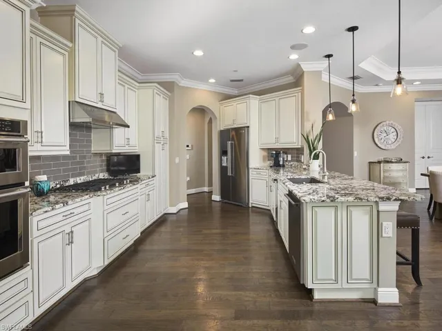 Kitchen with appliances with stainless steel finishes, decorative light fixtures, sink, a kitchen bar, and kitchen peninsula