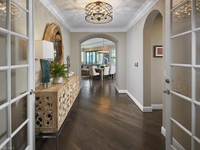 Hallway featuring crown molding, dark hardwood / wood-style floors, an inviting chandelier, and french doors