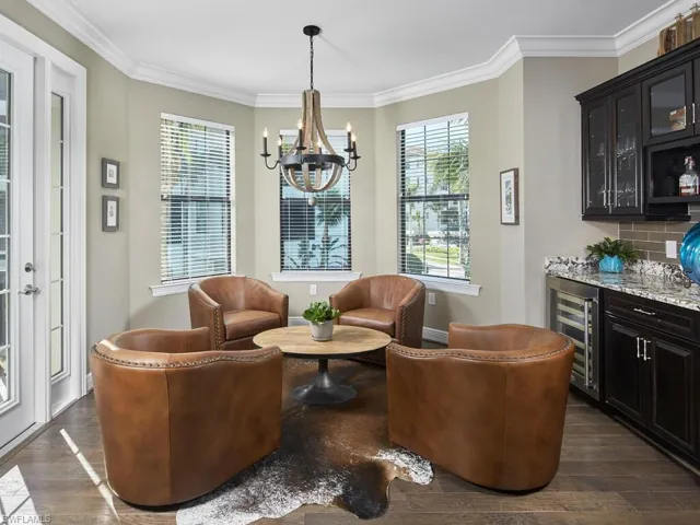 Living area with bar, dark hardwood / wood-style floors, wine cooler, ornamental molding, and a chandelier