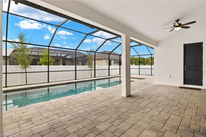 Large lanai entrance to pool bath and pool with privacy fence