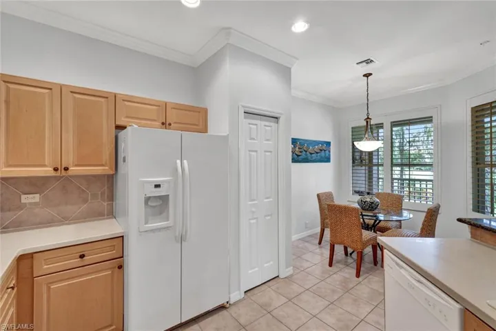 Kitchen with white appliances, crown molding, decorative backsplash, decorative light fixtures, and light tile patterned flooring