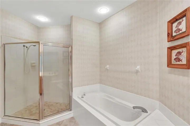 Full bath with wallpapered walls, a shower stall, a bath, and tile patterned flooring