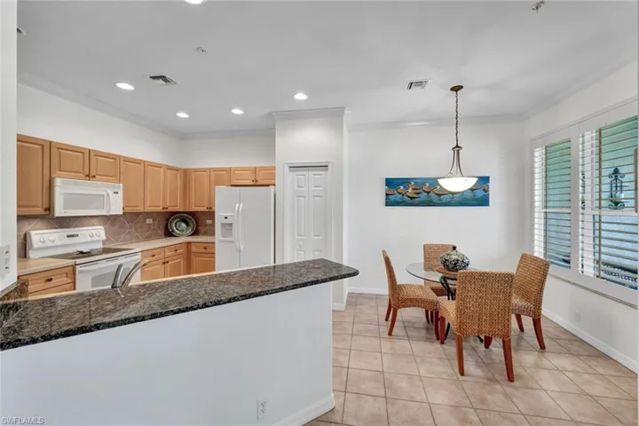 Kitchen with backsplash, white appliances, crown molding, light tile patterned floors, and recessed lighting