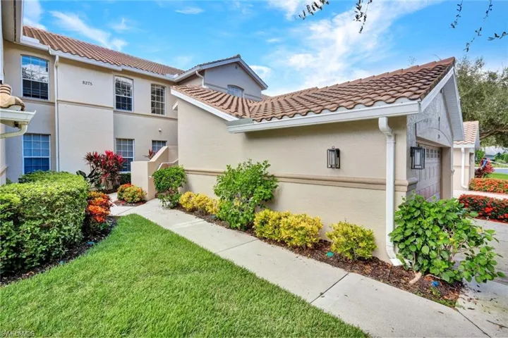 View of front of house featuring stucco siding, a tile roof, a garage, and a front lawn
