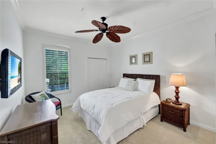 Bedroom with crown molding, carpet floors, a closet, and a ceiling fan