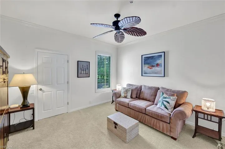 Living room with ornamental molding, carpet flooring, and ceiling fan