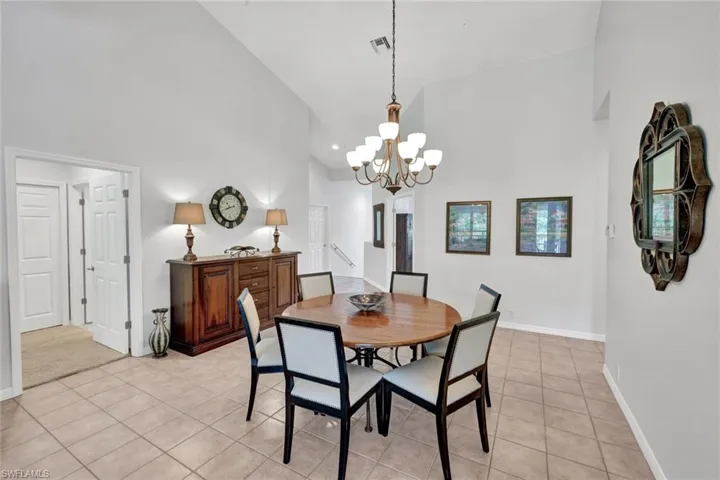 Dining room featuring high vaulted ceiling, light tile patterned floors, and a chandelier