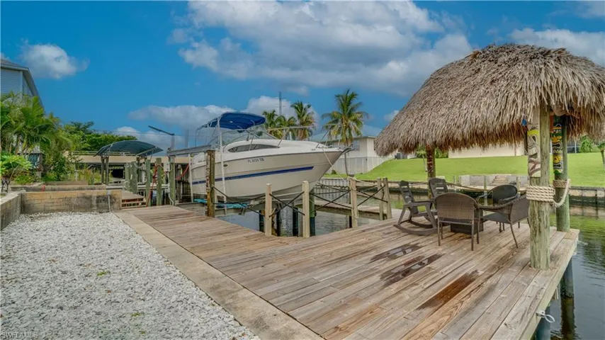 View of dock with boat lift and tiki hut
