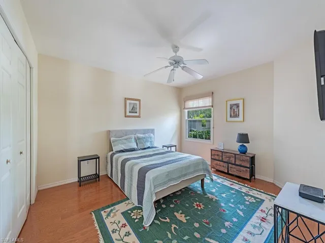 Guest Bedroom with double closet, ceiling fan, and hardwood / wood-style flooring