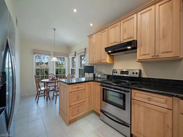 Kitchen featuring light tile patterned floors, stainless steel appliances, birch wood cabinets and eat in kitchen.