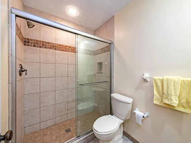 Bathroom featuring an enclosed shower, toilet, and tile patterned floors