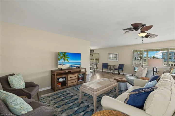 Living room with ceiling fan, wood finished floors, visible vents, and baseboards