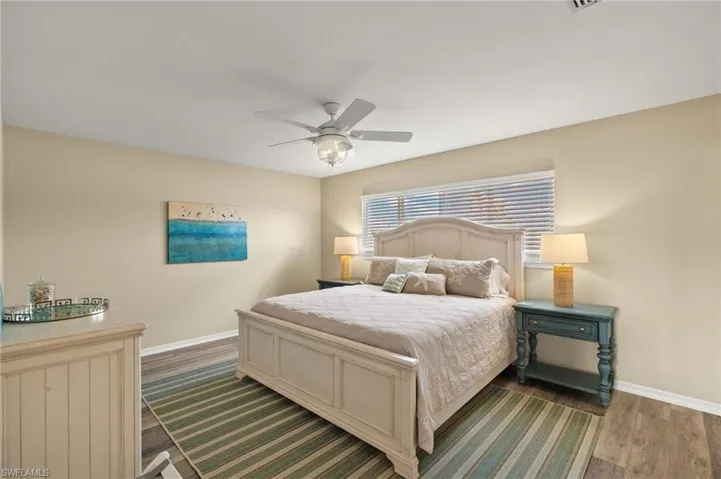 Bedroom featuring dark wood-type flooring, baseboards, and a ceiling fan