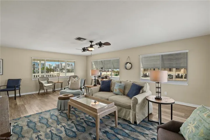 Living area with a ceiling fan, baseboards, visible vents, and wood finished floors
