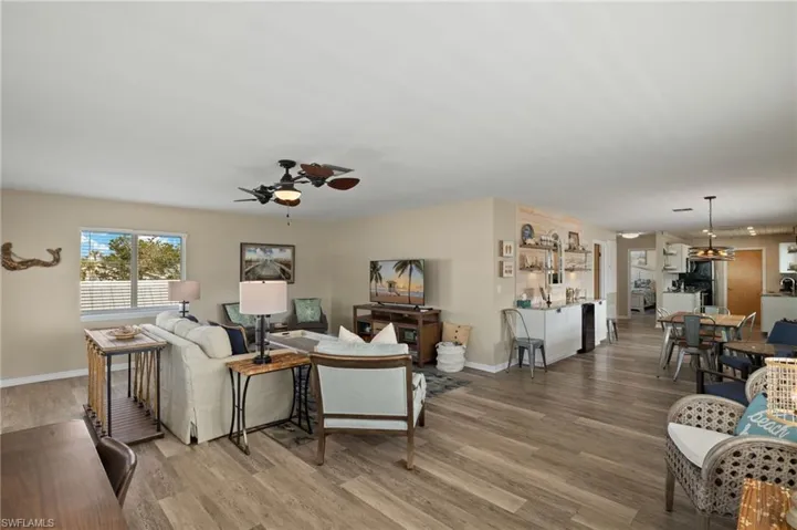 Living room with ceiling fan, light wood-style flooring, and baseboards