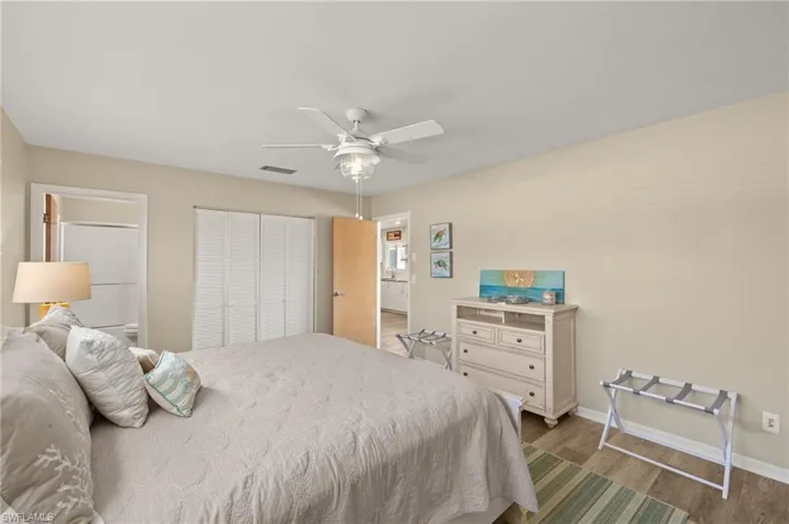 Bedroom with a closet, visible vents, ceiling fan, wood finished floors, and baseboards