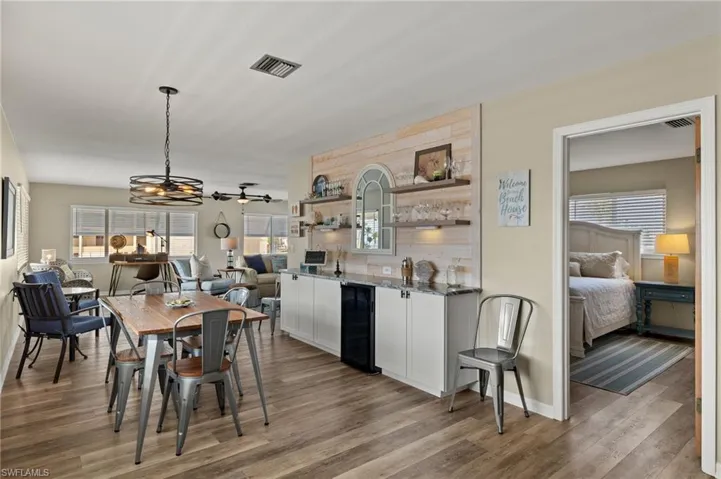 Dining space featuring beverage cooler, visible vents, indoor wet bar, and wood finished floors