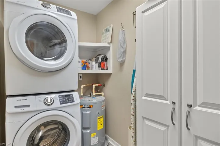 Laundry area featuring laundry area, stacked washer / dryer, and electric water heater