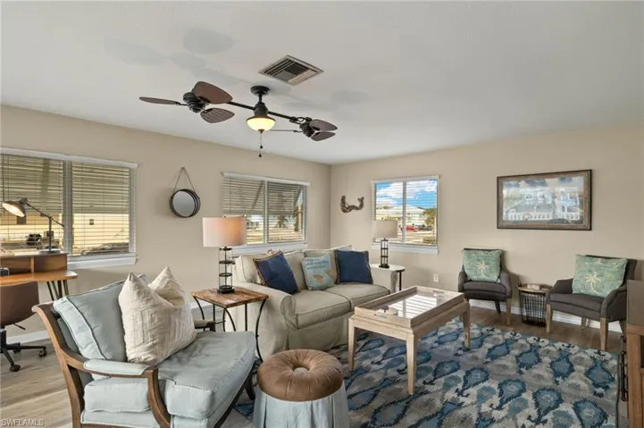 Living area with a ceiling fan, baseboards, visible vents, and wood finished floors