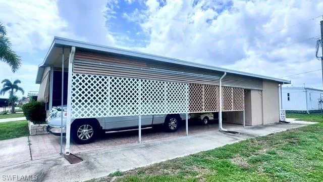 Carport featuring white lattice privacy screening and a concrete driveway