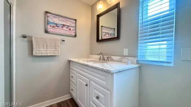 Bathroom vanity with white cabinetry, a marble-patterned countertop, and an undermount sink