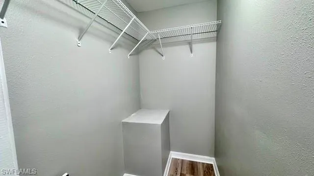 Walk-in closet with wire shelving, light gray walls, and wood-finish flooring