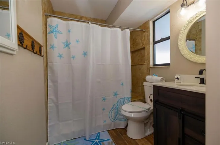 Bathroom featuring toilet, walk in shower, and vanity