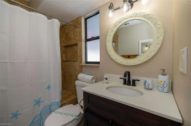 Bathroom with toilet, vanity, and a shower with shower curtain