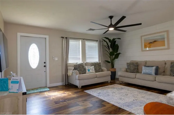 Living room with dark wood-type flooring and ceiling fan