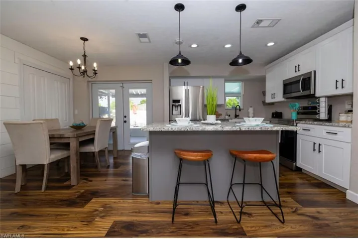 Kitchen with dark wood-type flooring, white cabinets, stainless steel appliances, and a kitchen island