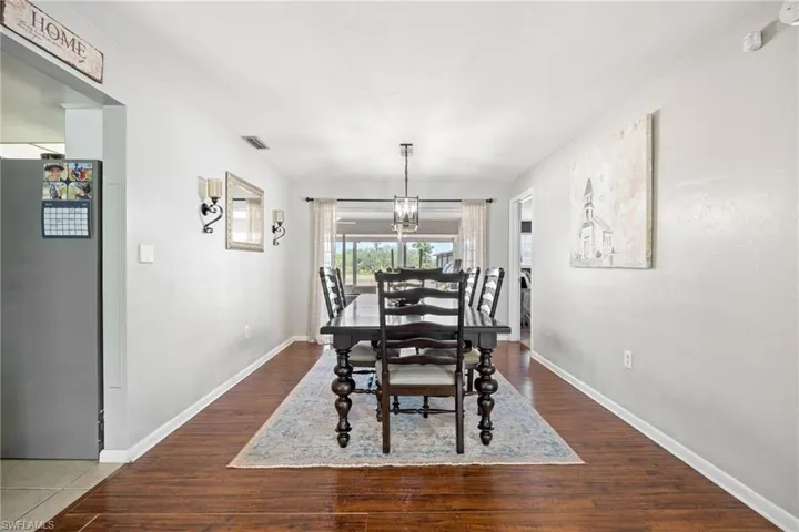 Dining space with baseboards, a chandelier, visible vents, and wood finished floors