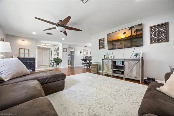 Living area featuring wood finished floors, a ceiling fan, visible vents, baseboards, and recessed lighting