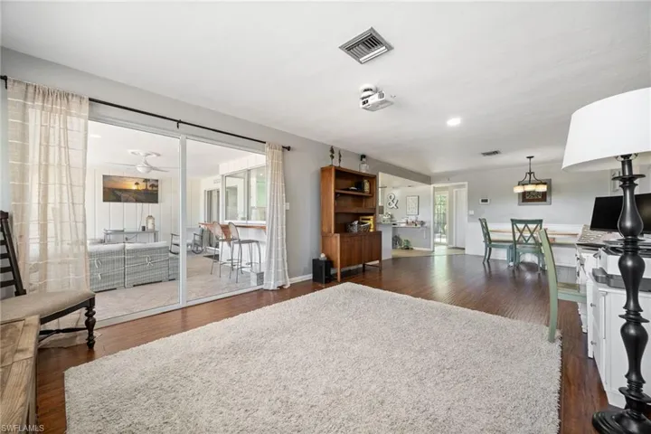 Living room with baseboards, visible vents, and dark wood-style floors