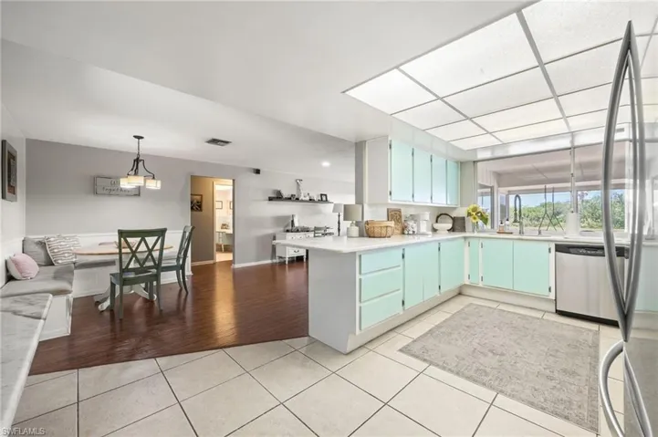 Kitchen featuring a peninsula, stainless steel dishwasher, visible vents, light countertops, and light tile patterned flooring