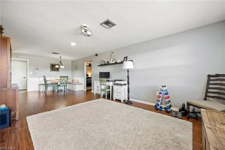 Living area with dark wood-style flooring, baseboards, visible vents, and recessed lighting