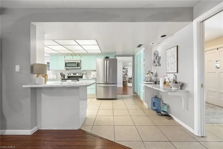 Kitchen featuring a peninsula, light countertops, appliances with stainless steel finishes, and light tile patterned floors