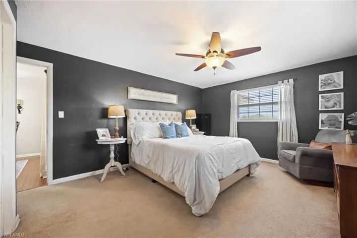 Bedroom with light carpet, baseboards, and a ceiling fan